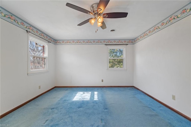 carpeted spare room featuring plenty of natural light and ceiling fan