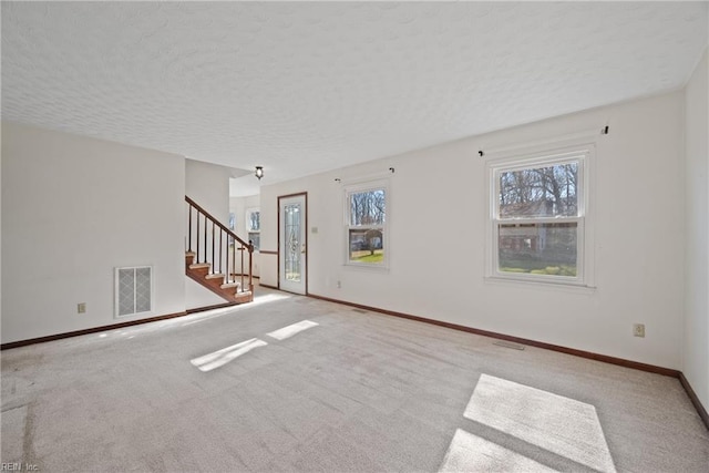 unfurnished room featuring light colored carpet and a textured ceiling