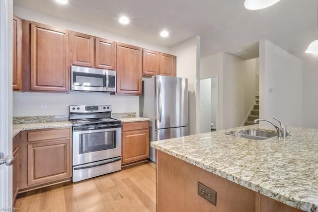 kitchen featuring light stone counters, appliances with stainless steel finishes, sink, and light hardwood / wood-style flooring