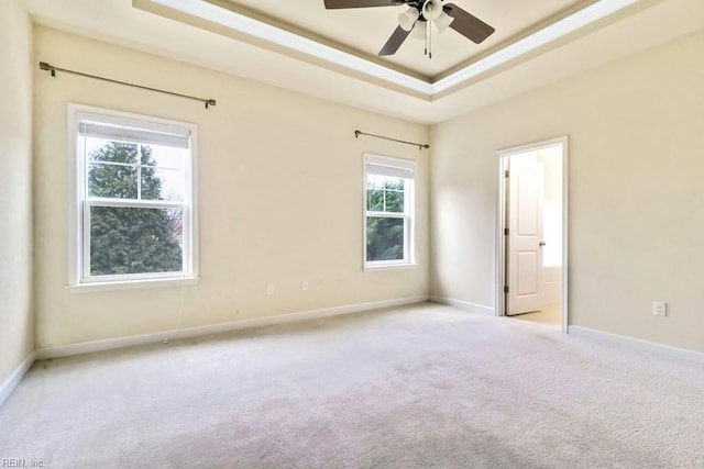 carpeted empty room with ceiling fan and a raised ceiling