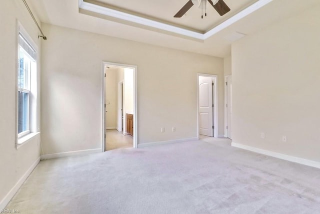 spare room featuring ceiling fan, a tray ceiling, and light carpet