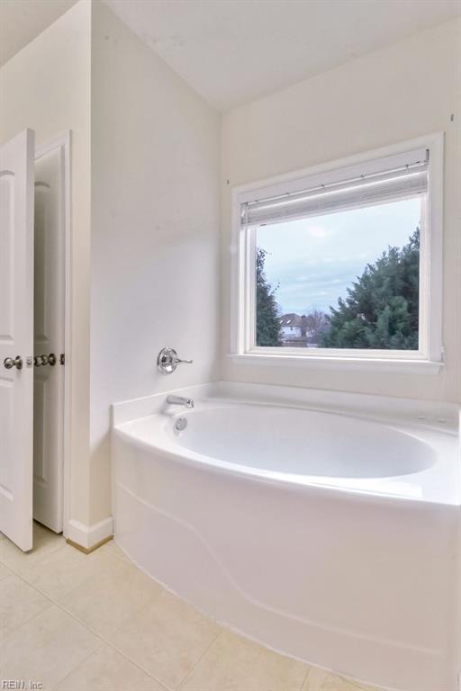 bathroom with tile patterned flooring and a tub