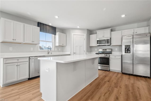 kitchen with sink, a center island, light wood-type flooring, stainless steel appliances, and white cabinets