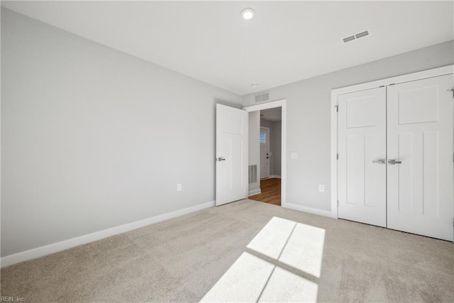 unfurnished bedroom with light colored carpet and a closet