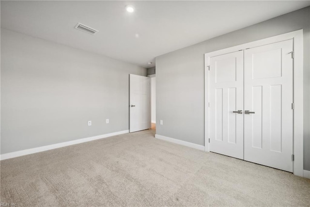 unfurnished bedroom with light colored carpet and a closet