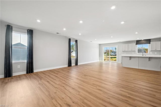 unfurnished living room with sink and light hardwood / wood-style floors