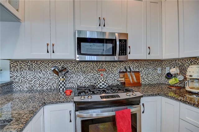 kitchen featuring white cabinetry, tasteful backsplash, stainless steel appliances, and dark stone counters