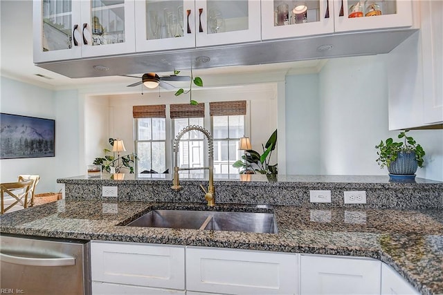 kitchen with sink, white cabinetry, dark stone countertops, dishwasher, and ceiling fan