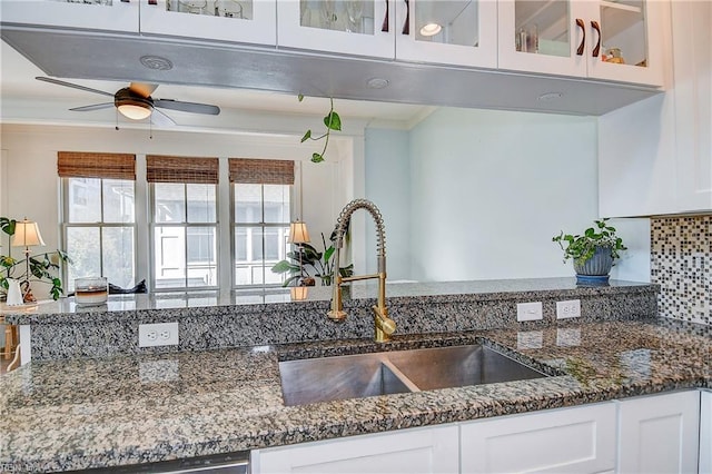 kitchen featuring white cabinetry, sink, dark stone countertops, ornamental molding, and ceiling fan