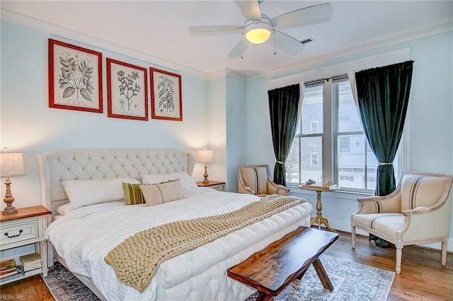 bedroom featuring ceiling fan, ornamental molding, and wood-type flooring