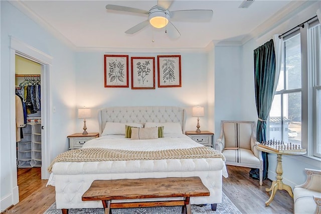 bedroom featuring light hardwood / wood-style flooring, crown molding, a walk in closet, and a closet