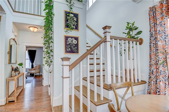 stairway featuring wood-type flooring and a high ceiling