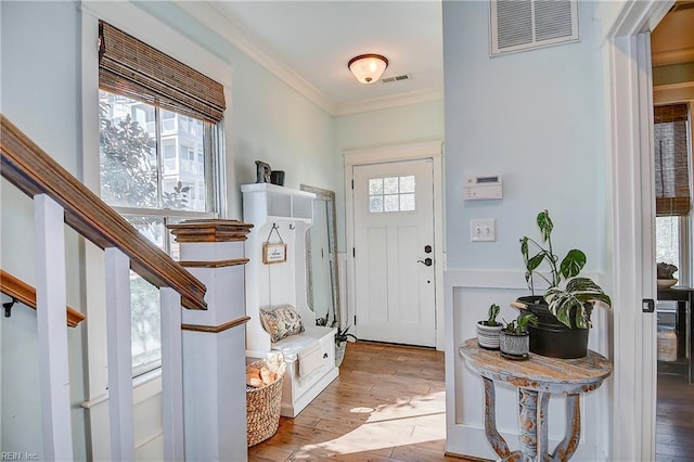 foyer entrance with plenty of natural light, ornamental molding, and light hardwood / wood-style floors