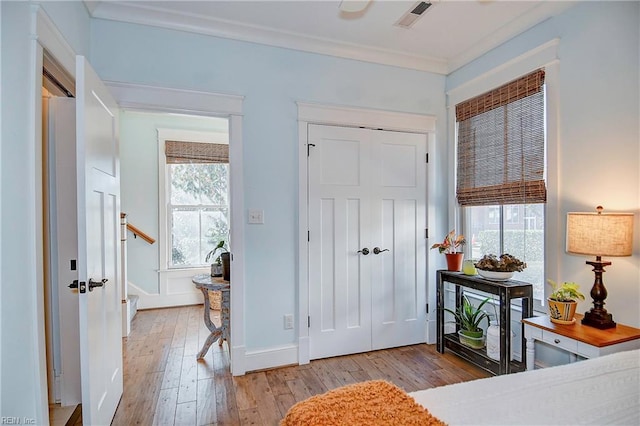 foyer with crown molding and light hardwood / wood-style floors