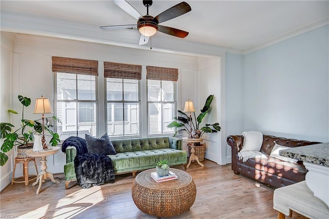 living room with ornamental molding, plenty of natural light, ceiling fan, and light wood-type flooring