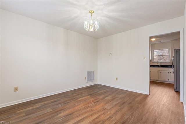 empty room featuring sink, a notable chandelier, and dark hardwood / wood-style flooring