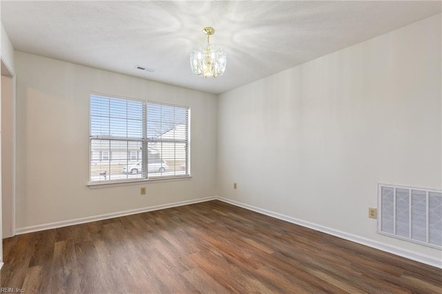 unfurnished room with dark wood-type flooring and a notable chandelier