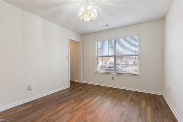 spare room with an inviting chandelier and dark hardwood / wood-style flooring