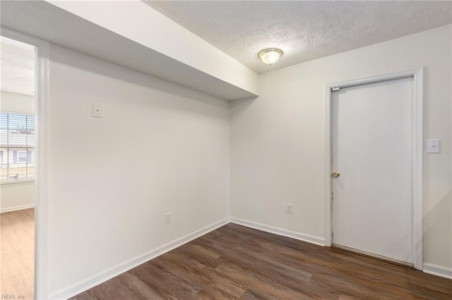 empty room with dark hardwood / wood-style flooring and a textured ceiling