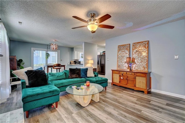 living room with hardwood / wood-style flooring, a textured ceiling, and ceiling fan