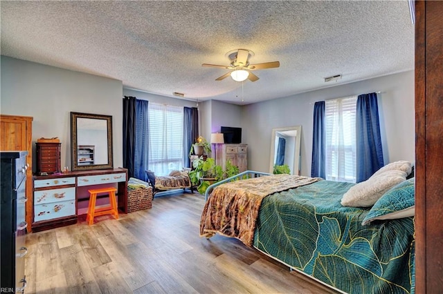 bedroom featuring a textured ceiling, light hardwood / wood-style floors, and ceiling fan