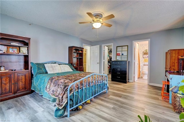 bedroom featuring a spacious closet, connected bathroom, a textured ceiling, and light wood-type flooring