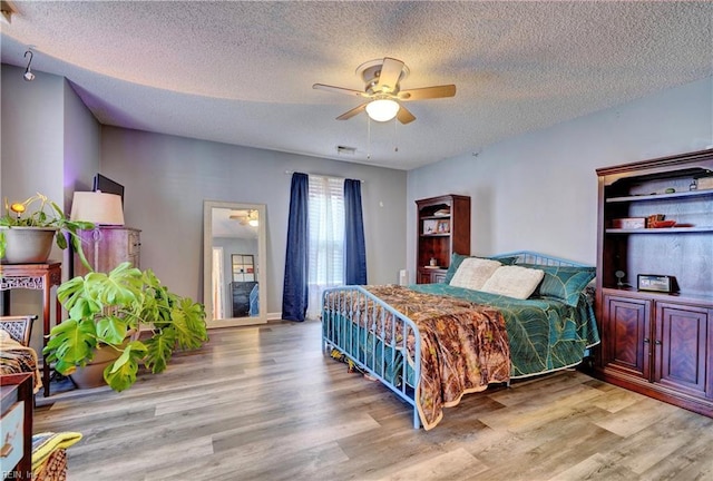 bedroom with ceiling fan, a textured ceiling, and light wood-type flooring