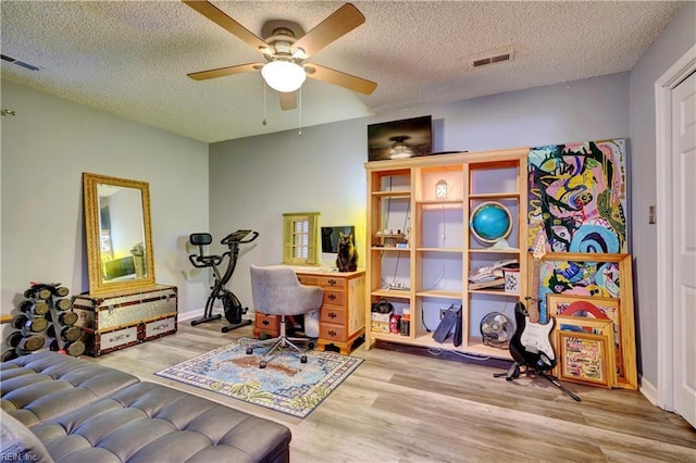 home office featuring ceiling fan, light hardwood / wood-style floors, and a textured ceiling