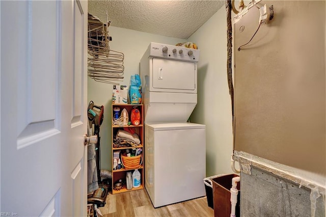 laundry area featuring stacked washer and dryer, light hardwood / wood-style flooring, and a textured ceiling