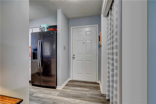 corridor with light hardwood / wood-style floors and a textured ceiling