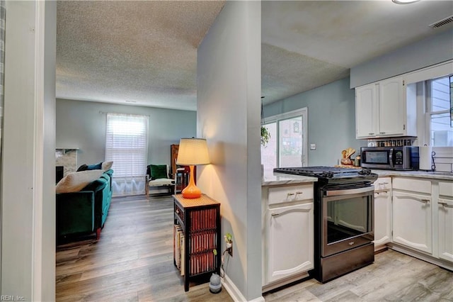 kitchen featuring appliances with stainless steel finishes, sink, white cabinets, light hardwood / wood-style floors, and a textured ceiling