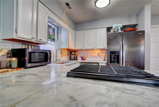 kitchen featuring sink, stainless steel appliances, light stone counters, tasteful backsplash, and white cabinets