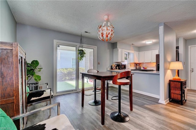 dining space featuring light hardwood / wood-style flooring and a textured ceiling