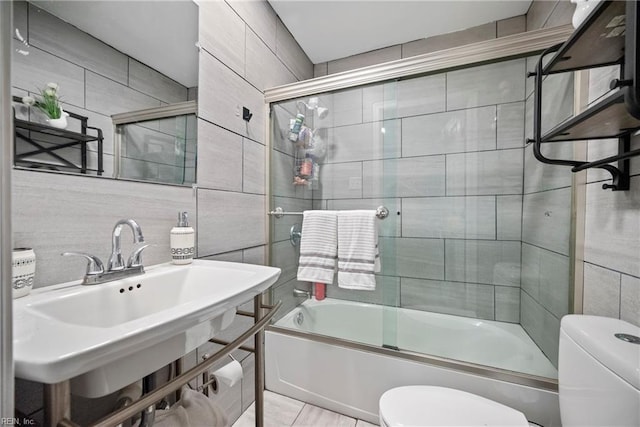 full bathroom featuring toilet, sink, shower / bath combination with glass door, tile walls, and backsplash