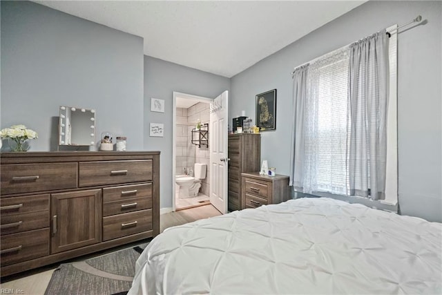 bedroom with ensuite bathroom and light wood-type flooring