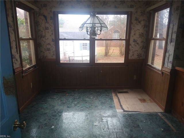 unfurnished dining area with a notable chandelier and wooden walls