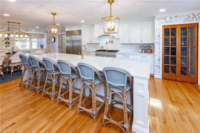 kitchen with high quality appliances, sink, pendant lighting, and white cabinets