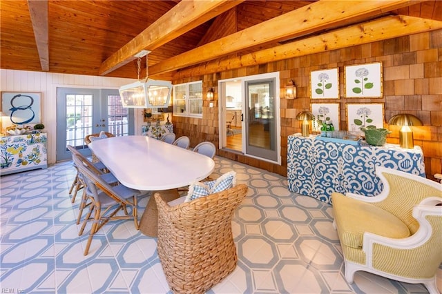 dining space with french doors, wood walls, an inviting chandelier, lofted ceiling with beams, and wooden ceiling