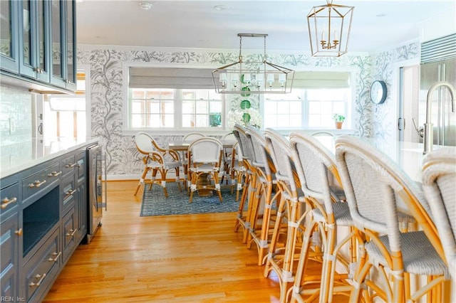 dining area with crown molding, beverage cooler, and light wood-type flooring