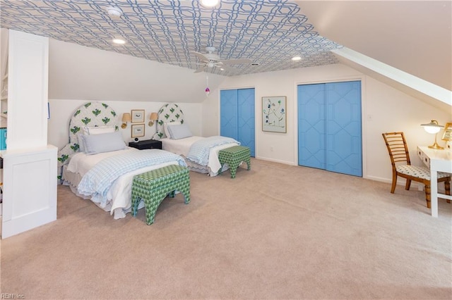 bedroom featuring ceiling fan, light colored carpet, lofted ceiling, and two closets