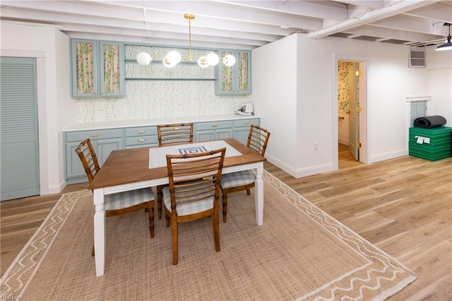 dining room featuring beam ceiling and light hardwood / wood-style flooring