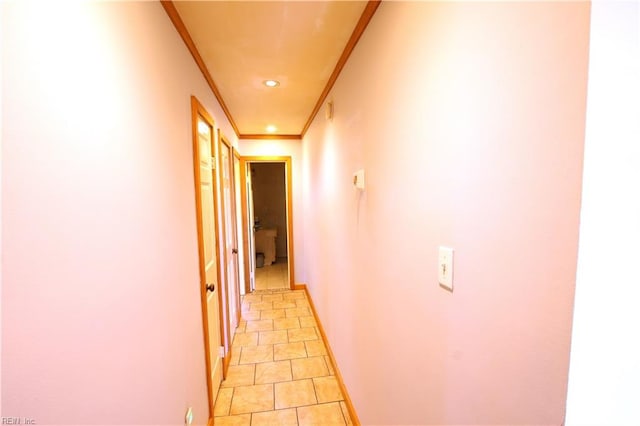 hallway with light tile patterned floors and crown molding