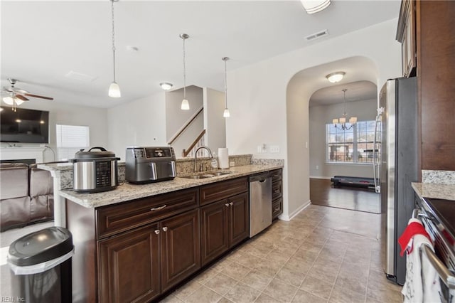 kitchen featuring light stone countertops, appliances with stainless steel finishes, sink, and pendant lighting