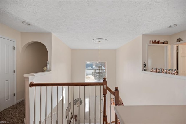 hallway featuring carpet floors, a chandelier, and a textured ceiling