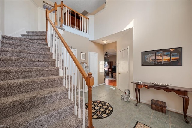 stairway with a towering ceiling and tile patterned floors