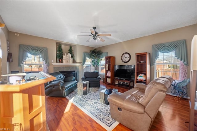 living room with hardwood / wood-style flooring, a tile fireplace, a wealth of natural light, and ceiling fan