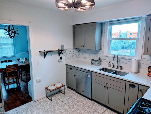 kitchen with sink, stainless steel dishwasher, gray cabinets, pendant lighting, and decorative backsplash