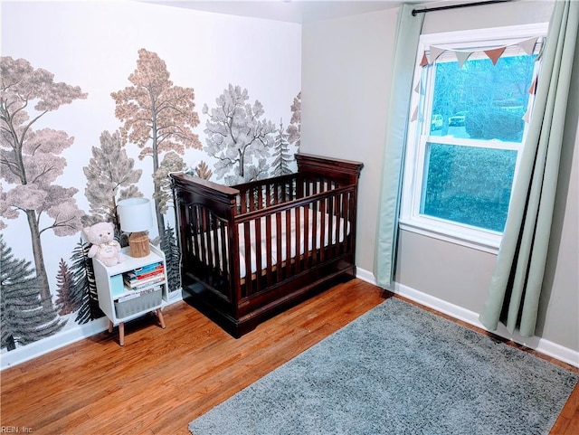 bedroom with hardwood / wood-style flooring and a crib