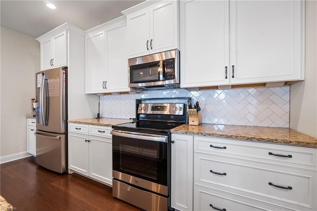 kitchen with dark wood-type flooring, white cabinetry, appliances with stainless steel finishes, light stone countertops, and backsplash