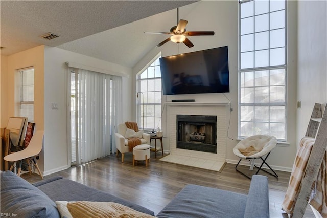 living room featuring hardwood / wood-style flooring, ceiling fan, lofted ceiling, and a textured ceiling